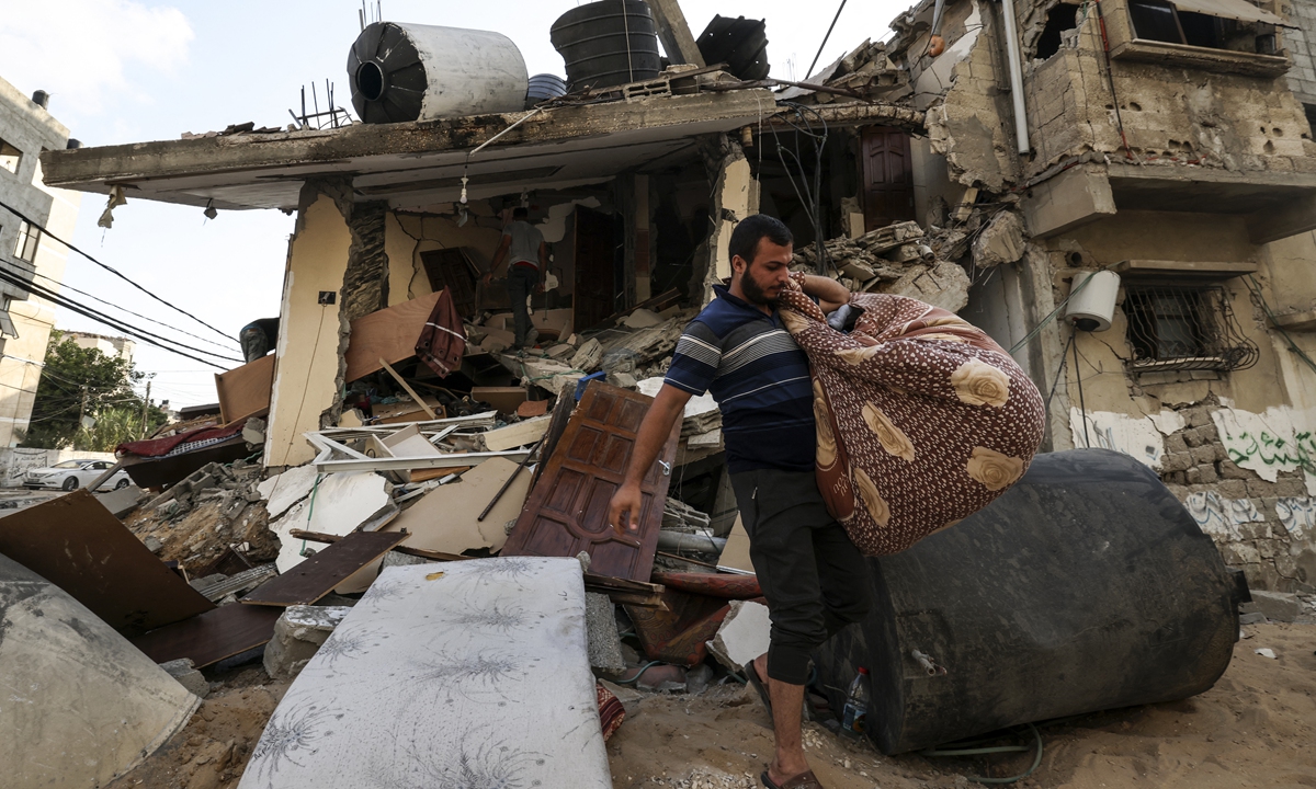 Palestinians salvage belongings from the rubble of their home, following Israeli air strikes in Gaza City, on August 7, 2022.Photo: AFP