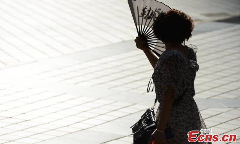 A woman walks in the street with a fan to beat the heat in Chongqing, Aug. 17, 2022. The highest temperature recorded was 44.6 ℃ in Chongqing on Wednesday. (Photo: China News Service/He Penglei)