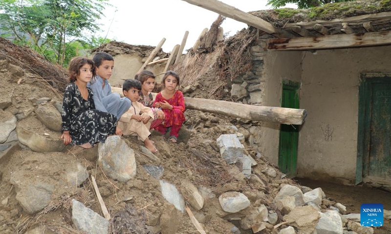 Children sit on the rubbles of houses destroyed by flood in Nuristan province, Afghanistan, Aug. 18, 2022.(Photo: Xinhua)