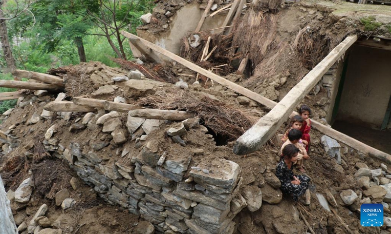 Children sit on the rubbles of houses destroyed by flood in Nuristan province, Afghanistan, Aug. 18, 2022.(Photo: Xinhua)