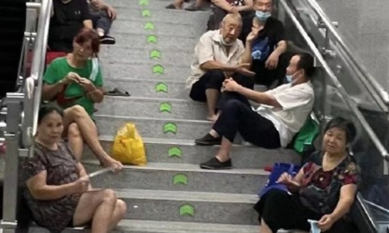 Many people of Sichuan Province and Chongqing Municipality sitting on the sides of the stairs on their own benches, while others playing cards in the spacious area. Screenshot of Sichuan Observation