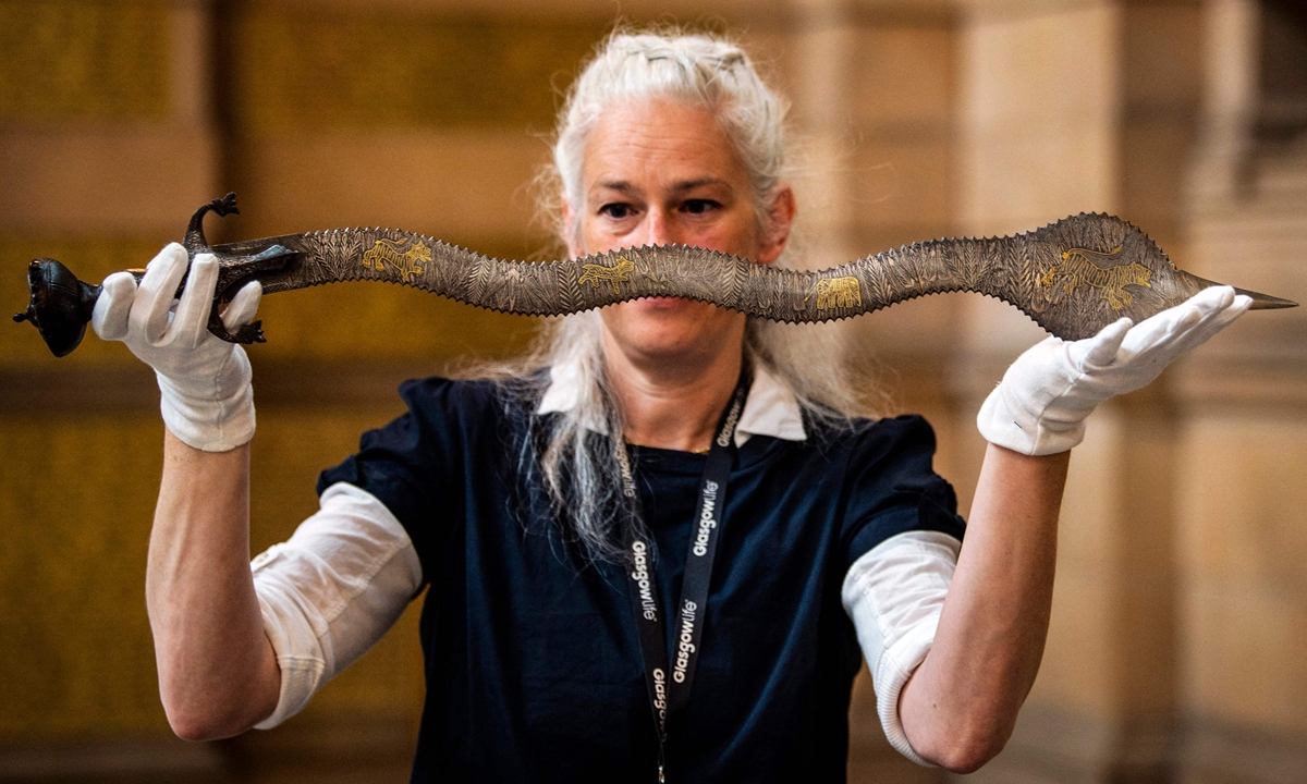 A museum conservator holds a ceremonial Indo-Persian sword during a ceremony at Kelvingrove Art Gallery and Museum in Glasgow on August 19, 2022 as the UK prepares to repatriate Indian artifacts. Glasgow is returning seven Indian cultural artifacts looted during British colonial rule. Photo: VCG