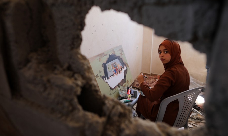 A Palestinian artist is seen painting at the damaged house of the deceased artist Donyana al-Amour in the southern Gaza Strip city of Khan Younis, on Aug. 23, 2022.(Photo: Xinhua)