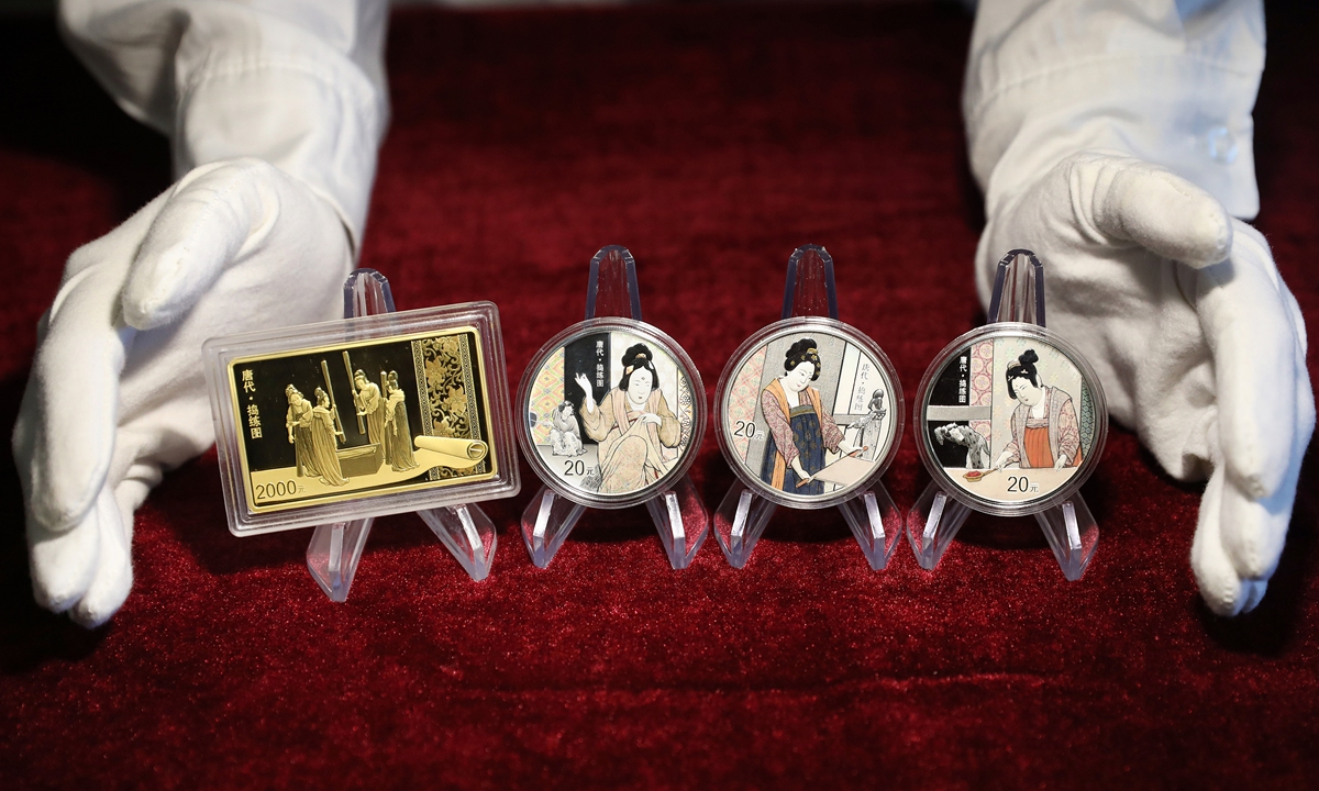 An employee of China Gold Coin Group Co. presents a set of gold and silver commemorative coins featuring an ancient Chinese silk painting. The coins, to be issued on August 29, 2022, were designed using a combination of ink, paper and bamboo leaves, complemented by scenes from the painting. Photo: CFP