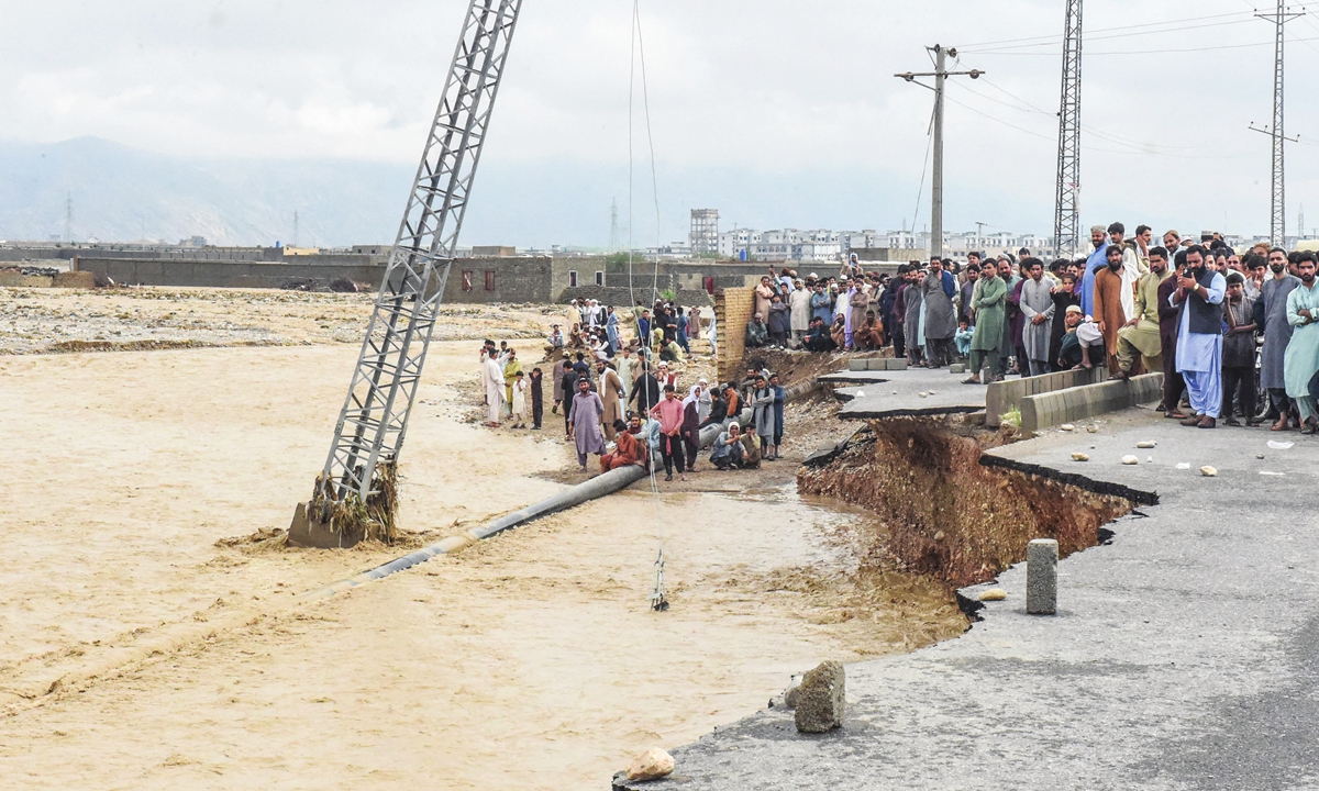 People gather along a road damaged by flooding after heavy monsoon rainfalls in Quetta, Pakistan, on August 26, 2022. Heavy rain continued to pound parts of the country on August 26 after the government declared an emergency to deal with monsoon flooding that it said had affected over 4 million people. Photo: AFP