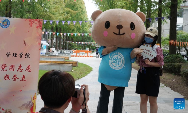 A freshman takes a photo with a mascot at Fudan University in east China's Shanghai, Aug. 28, 2022.Photo:Xinhua