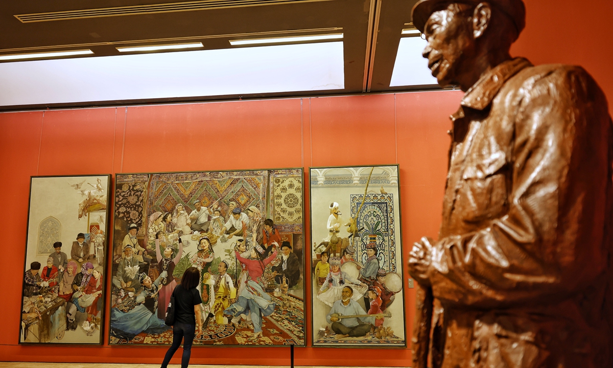 A visitor looks at paintings depicting the happy lives of people in Northwest China's Xinjiang Uygur Autonomous Region during the 13th China Art Festival held at the National Art Museum of China in Beijing, on September 2, 2022. The exhibition focuses on China's progress and development in the new era. Photo: Li Hao/GT