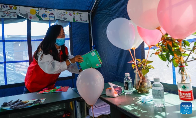 Luo Lian arranges books in a tent classroom at the quake relief shelter of Luding No. 2 high school in Luding County, southwest China's Sichuan Province, Sept. 10, 2022.Photo:Xinhua