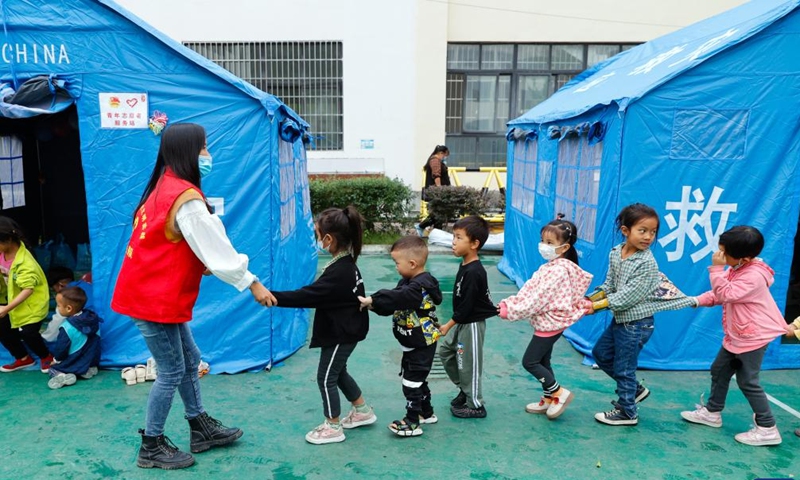 Luo Lian leads children to a tent classroom at the quake relief shelter of Luding No. 2 high school in Luding County, southwest China's Sichuan Province, Sept. 10, 2022.Photo:Xinhua