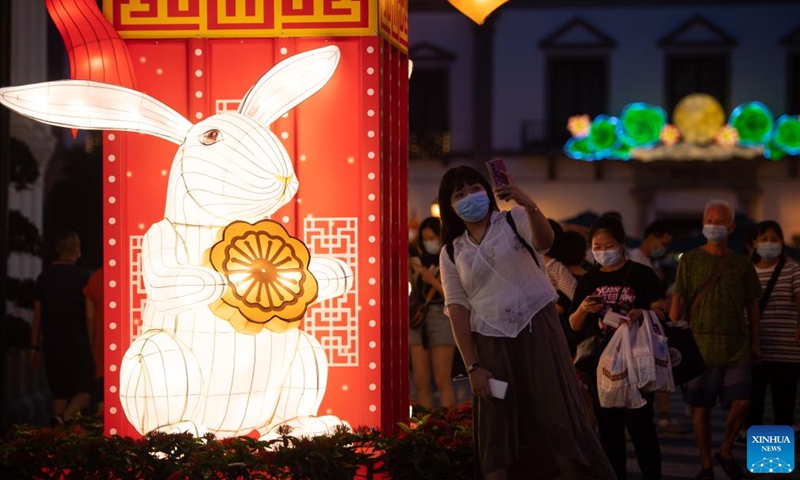 A woman takes selfies with an illumination installation during the Mid-Autumn Festival at Senado Square in south China's Macao, Sept. 10, 2022.Photo:Xinhua