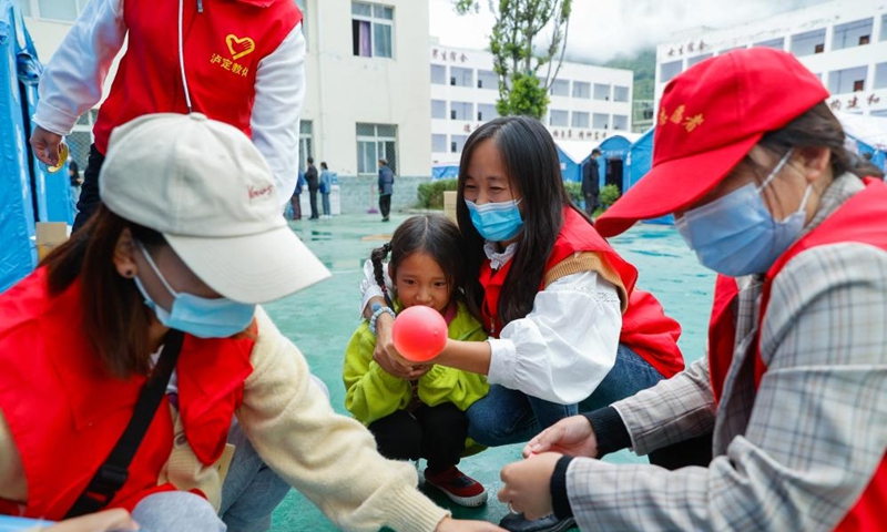 A girl helps Luo Lian (2nd R) and other volunteers blow up balloons at the quake relief shelter of Luding No. 2 high school in Luding County, southwest China's Sichuan Province, Sept. 10, 2022.Photo:Xinhua