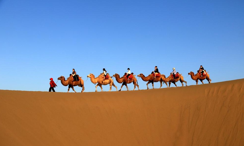 Tourists ride on camels during Mid-Autumn Festival holiday at Mingsha Mountain and Crescent Spring scenic spot in Dunhuang City, northwest China's Gansu Province, Sept. 10, 2022.Photo:Xinhua