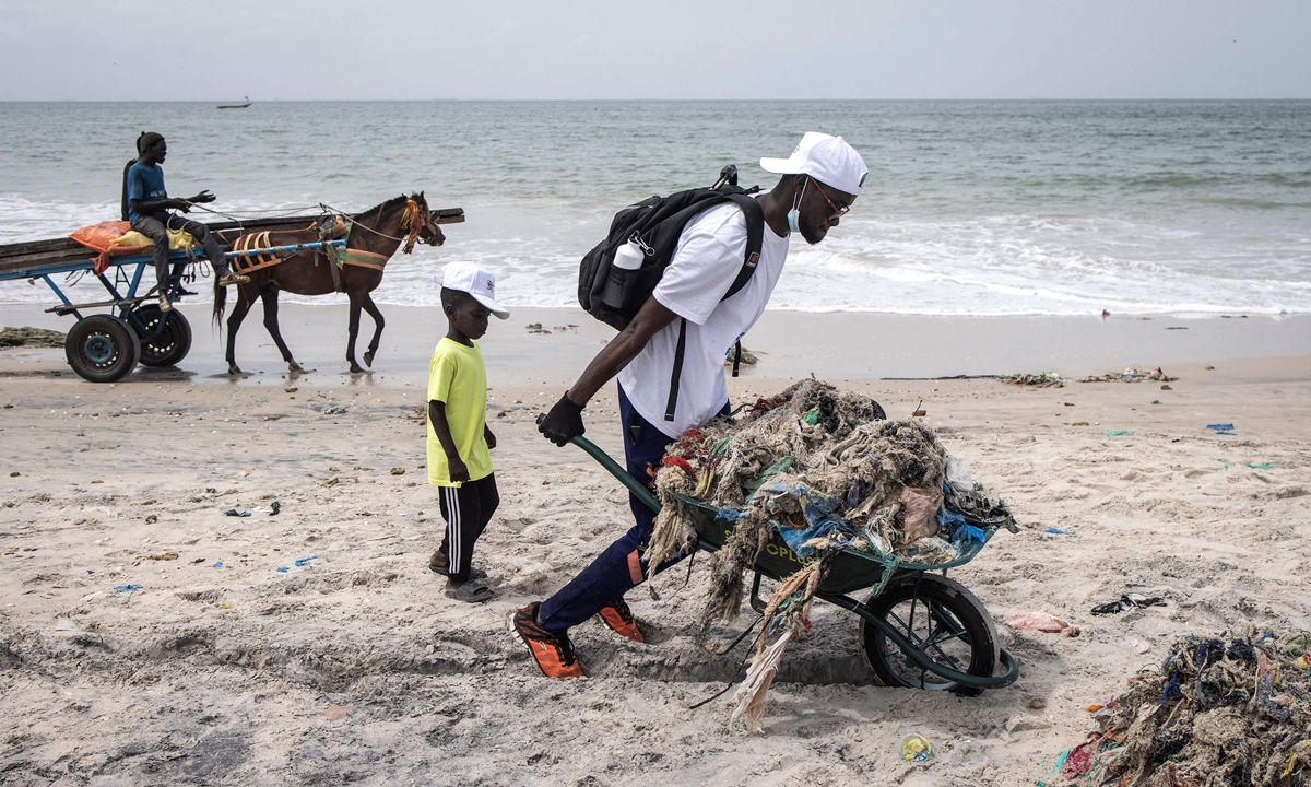 A volunteer collects waste along the coastline during the 