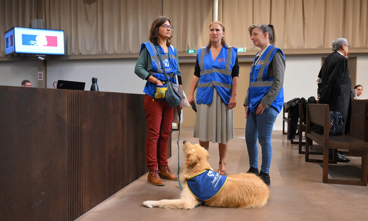 Members of a victim assitance association stand with a service dog before the opening of a case in Marseille, France, on September 19, 2022. The presence of an emotional support dog during the hearing allows attendees to relax. Photo: VCG