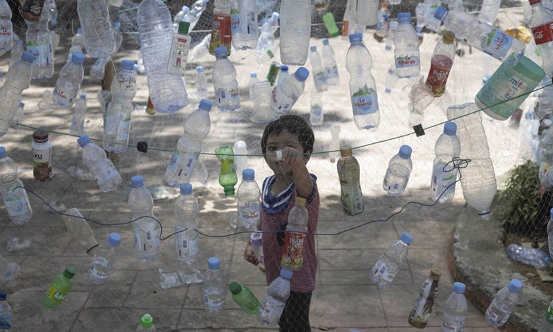 A boy views an installation made of plastic bottles during the Marine Debris Festival, held by the local community as a campaign to save the beach from plastics pollution, in Poliwali Mandar district, West Sulawesi, Indonesia, Oct. 3, 2021(Photo: Xinhua)