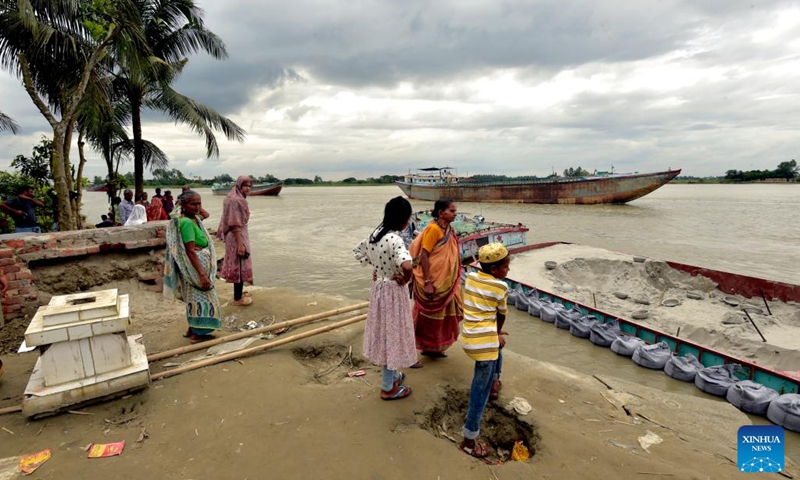 People stand on the eroded river bank in Munshiganj district, Bangladesh, Sept. 19, 2022. Residents of a village in Munshiganj district have lived amid worries over the last couple of months since Padma river took a serious turn at the start of this monsoon and continued devouring most of the homesteads and vast croplands.(Photo: Xinhua)