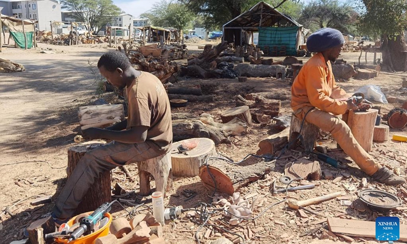 Artists work on their pieces of artworks at a marketplace in Okahandja, Namibia, on Sept. 20, 2022. Namibian artists are maximizing wood carving tradition to preserve cultural heritage and access bigger markets from an open space along the main road in Okahandja, a town 70 km north of Windhoek, the capital of Namibia.(Photo: Xinhua)