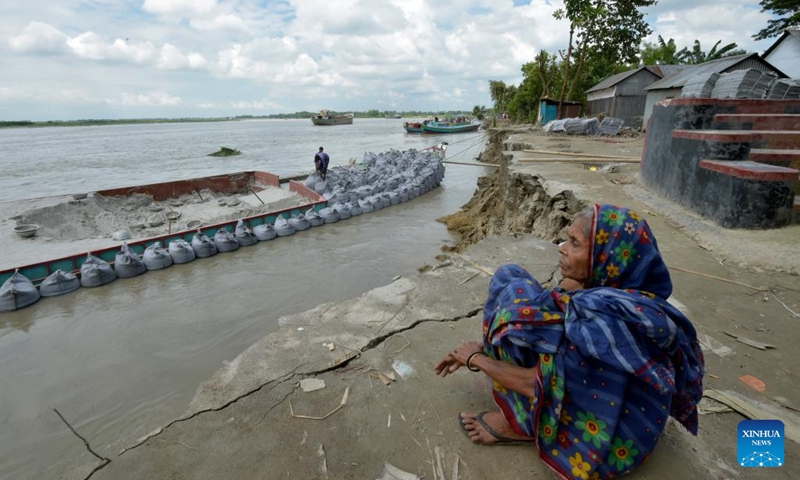 An elderly woman sits on the eroded river bank in Munshiganj district, Bangladesh, Sept. 19, 2022. Residents of a village in Munshiganj district have lived amid worries over the last couple of months since Padma river took a serious turn at the start of this monsoon and continued devouring most of the homesteads and vast croplands.(Photo: Xinhua)