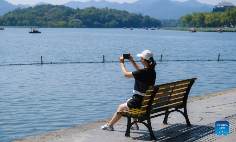 A tourist takes photos of the West Lake scenic area during the National Day holiday in Hangzhou, east China's Zhejiang Province, Oct. 2, 2022. (Xinhua/Xu Yu)