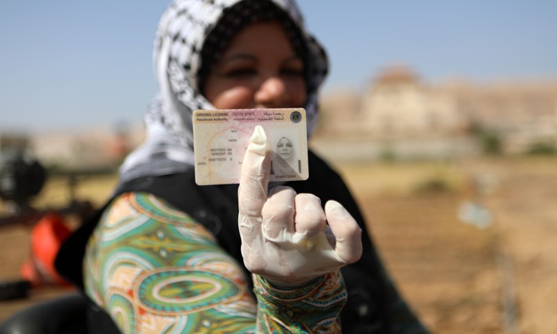 Palestinian female farmer Etihad Ayyad displays her tractor license on a tractor in the West Bank city of Jericho, on Sept. 24, 2022. (Photo: Xinhua)