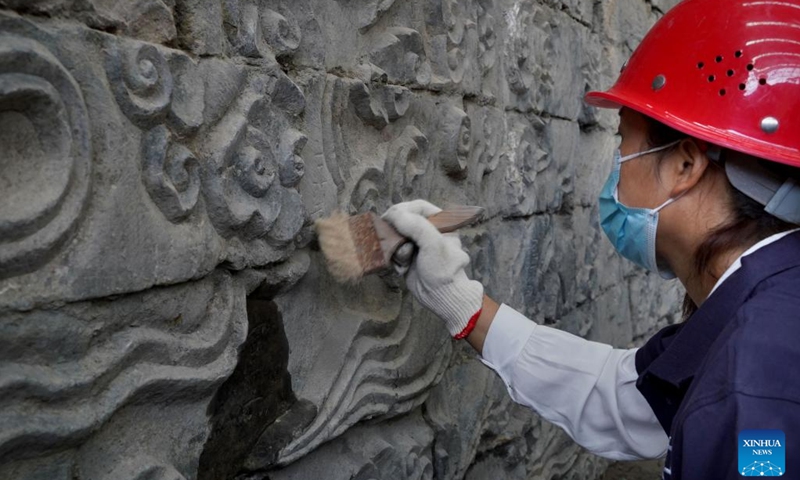 A staff member cleans a stone mural discovered in the Zhouqiao relics site in Kaifeng City, central China's Henan Province, Sept. 21, 2022.(Photo: Xinhua)