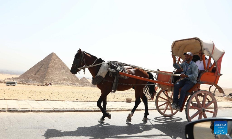 Tourists take a carriage while visiting the Giza Pyramids scenic spot during the World Tourism Day in Giza, Egypt, Sept. 27, 2022. Egypt on Tuesday opened most of its museums and archaeological sites, including the Giza Pyramids, to visitors for free on the occasion of the World Tourism Day.(Photo: Xinhua)