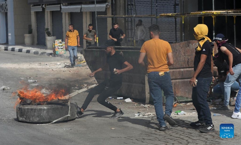 Protesters burn a tire during clashes with Israeli soldiers in the West Bank city of Jenin, Oct. 8, 2022.(Photo: Xinhua)