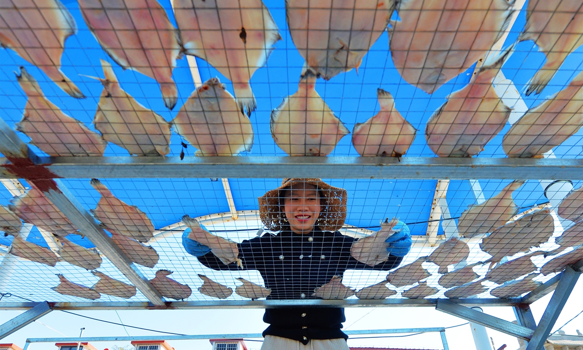 A woman makes dried fish in Qingdao, East China's Shandong Province, on October 19, 2022. Shandong is a major fishing province, with 238 fishing ports and about 2.05 million people working in the sector. It has a coastline of more than 3,500 kilometers, accounting for one-sixth of China's total. Photo: cnsphoto