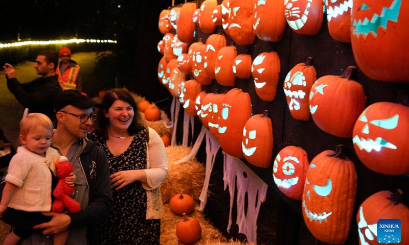 People look at the illuminated pumpkin installations at the Pumpkins After Dark event in Burnaby, Canada, on Oct. 9, 2022. The outdoor walk-through event features illuminated pumpkin sculptures and displays built by over 6,000 handcrafted pumpkins, together with music, sounds, and special effects.(Photo: Xinhua)