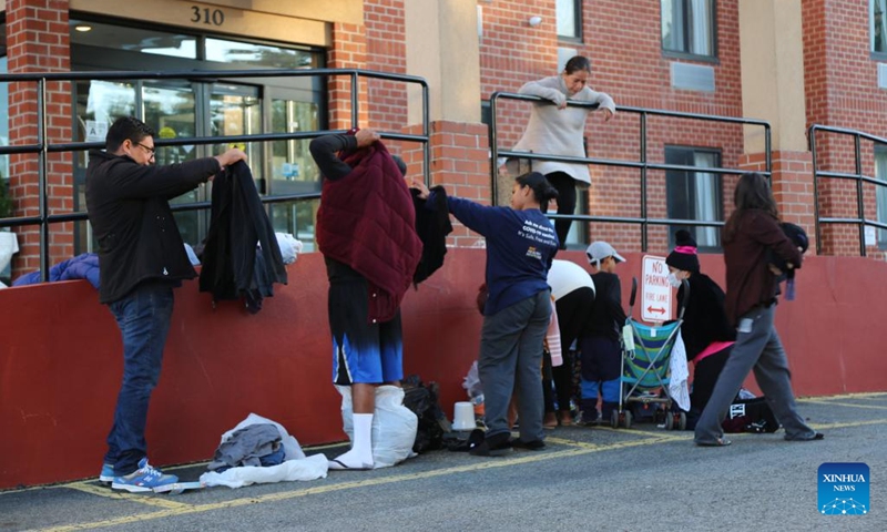 Antonio Ovando (1st L), an asylum seeker who arrived in New York City less than a week ago, picks up clothes dropped off by New Yorkers outside a hotel in Staten Island, New York, the United States, on Oct. 9, 2022. The thousands of newly arrived asylum seekers in New York City, the most populous city in the United States, are facing multifaceted challenges in taking roots amid an ongoing humanitarian crisis.(Photo: Xinhua)