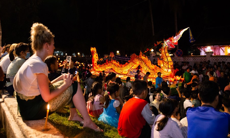 People carried lanterns and watched the dragon boats heading to Mekong River in the ancient town of Luang Prabang, a world heritage site on Oct. 11, 2022.(Photo: Xinhua)