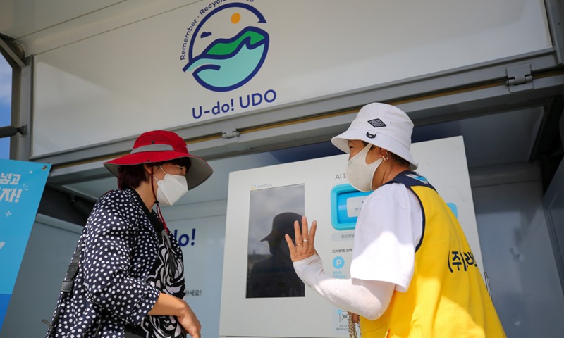 A worker introduces a plastic collection device to a tourist in Udo Island of Jeju, South Korea, Oct. 13, 2022.(Photo: Xinhua)