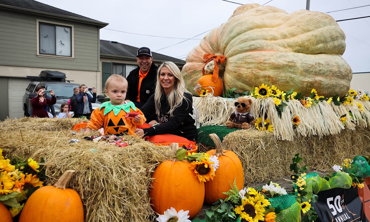 A man and his family pose besides their giant pumpkin, which weighs 2,560 pounds (1,161 kilograms), a new North American record, in Half Moon Bay, California, the US, on October 15, 2022. Thousands attended the Half Moon Bay Pumpkin Festival to see the giant pumpkin parade. Photo: IC