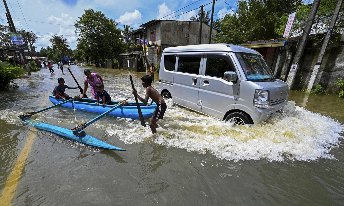 A van moves past children playing along a flooded street after heavy rains on the outskirts of Colombo, Sri Lanka, on October 16, 2022. The Department of Meteorology of the country said heavy showers would continue in several provinces. Photo: AFP