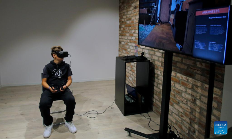 A boy experiences virtual reality goggles while visiting the 3rd edition of the new media art festival RADAR in Bucharest, capital of Romania, Oct. 16, 2022. (Photo by Cristian Cristel/Xinhua)