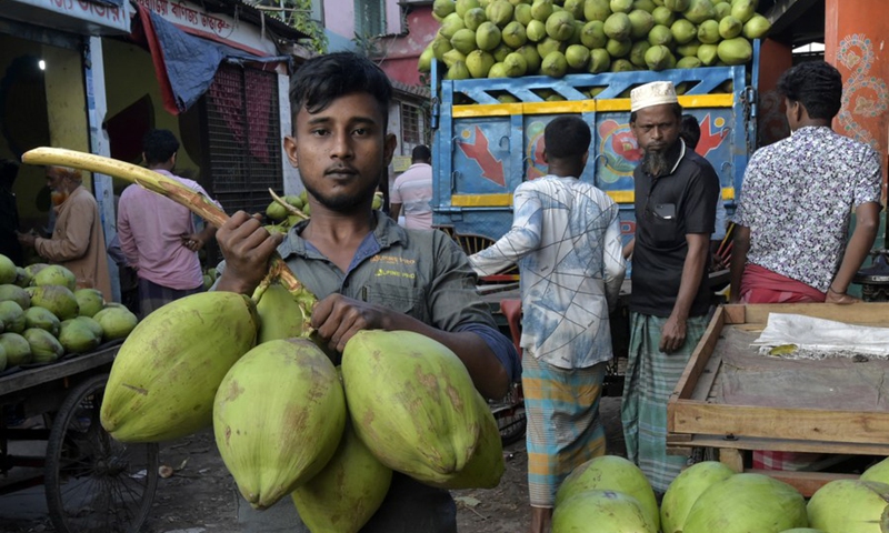 A worker is loading a van with tender coconuts at a marketplace in Dhaka, Bangladesh on Oct. 20, 2022.(Photo: Xinhua)