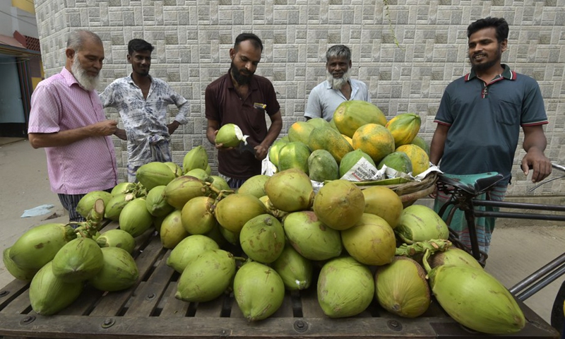 A vendor is cutting coconut for sale at a roadside shop in Dhaka, Bangladesh on Oct. 20, 2022.(Photo: Xinhua)