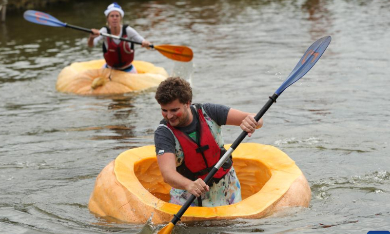 People compete in the pumpkin regatta in the village of Lichtaart of Kasterlee, Belgium, Oct. 23, 2022. The 13th edition of pumpkin regatta is a kayaking competition in Belgium, attracting participants to sit and compete in large hollow-out pumpkins. According to local organizers, the weight of each pumpkin that was made into a boat could reach hundreds of kilograms. Photo: Xinhua