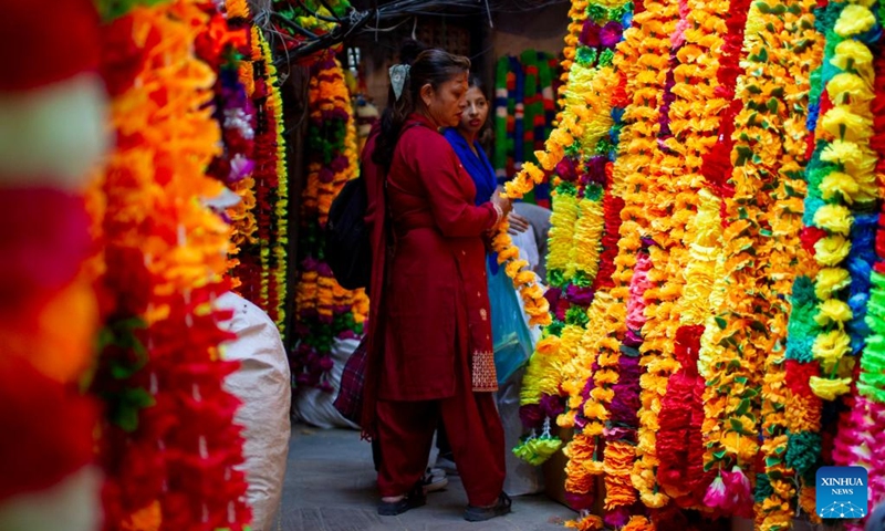 A woman shops at a garland store for the Tihar festival, or festival of lights, in Kathmandu, Nepal, Oct. 23, 2022. (Photo by Sulav Shrestha/Xinhua)