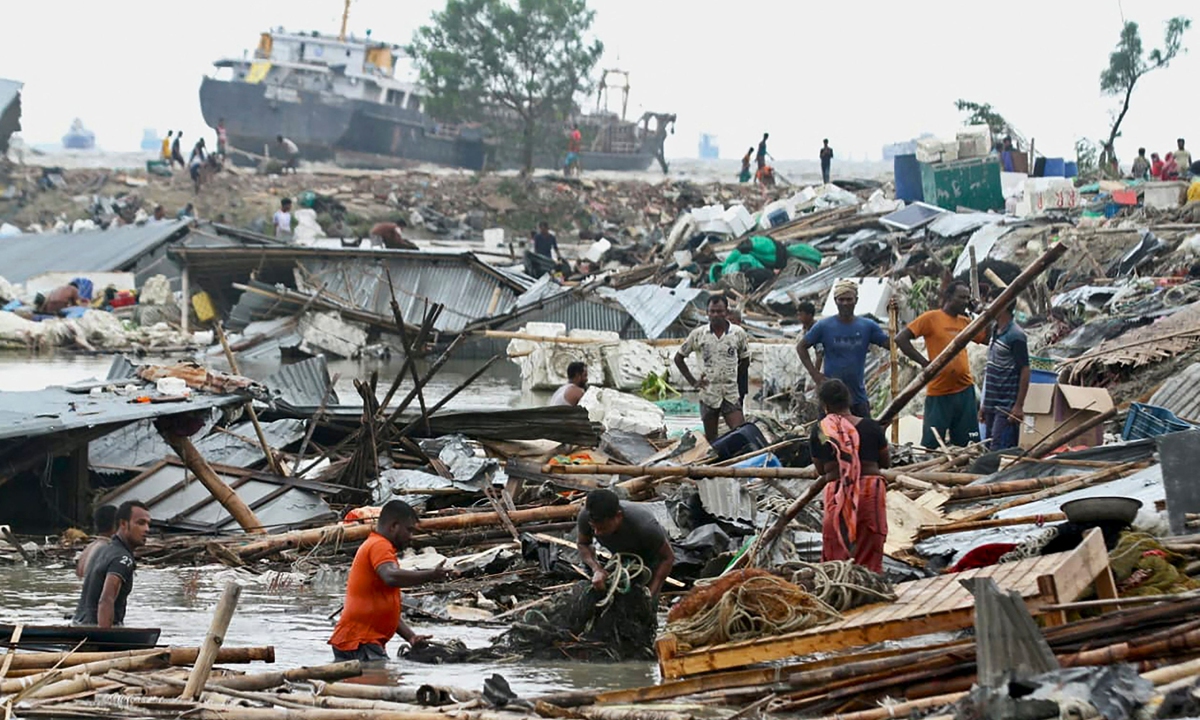 Residents search for their belongings amid the debis of their collapsed huts after the cyclone Sitrang hits in Chittagong on October 25, 2022. Photo: VCG