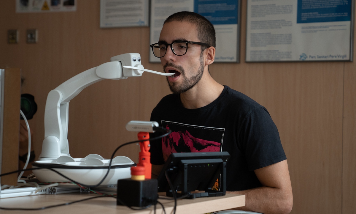 A man tests a prototype of a humanized robot that helps patients feed themselves during the presentation of the Barcelona Aging Collaboratory on October 26, 2022, in Barcelona, Spain. The Barcelona Aging Collaboratory is a new participatory space to co-create with older people innovative products and services for more active and healthy aging. Photo: VCG