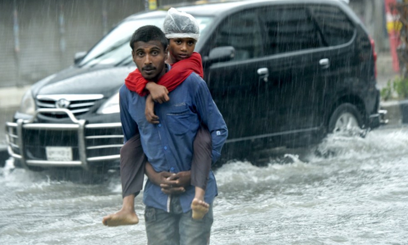 People walk on a waterlogged street in Bangladeshi capital Dhaka, on Oct. 24, 2022.(Photo: Xinhua)