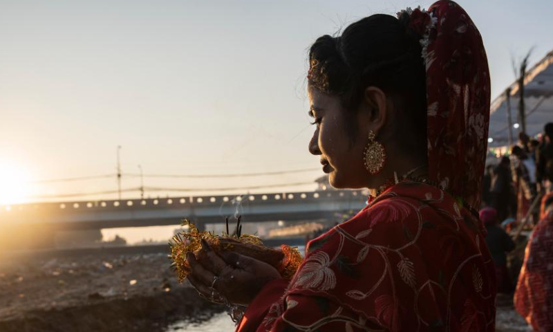 A woman worships the rising sun during the Chhath festival on the bank of the Bagmati River in Kathmandu, Nepal, Oct. 31, 2022. The Chhath festival is dedicated to the sun, which is regarded as a token of stability and prosperity, and a Vedic goddess Chhathi Maiya. (Photo by Hari Maharjan/Xinhua)