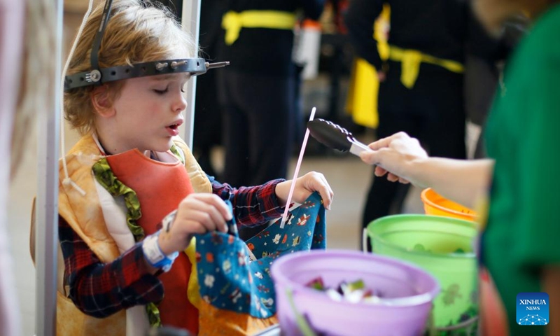 A young patient receives treats from costumed healthcare workers during a Trick-or-Treat party to celebrate the Halloween at British Columbia Children's Hospital in Vancouver, British Columbia, Canada, on Oct. 31, 2022.(Photo: Xinhua)