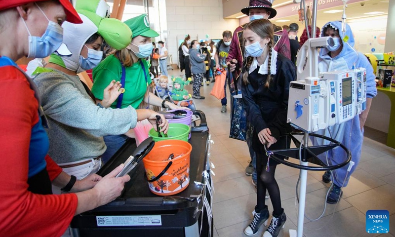 A young patient receives treats from costumed healthcare workers during a Trick-or-Treat party to celebrate the Halloween at British Columbia Children's Hospital in Vancouver, British Columbia, Canada, on Oct. 31, 2022.(Photo: Xinhua)