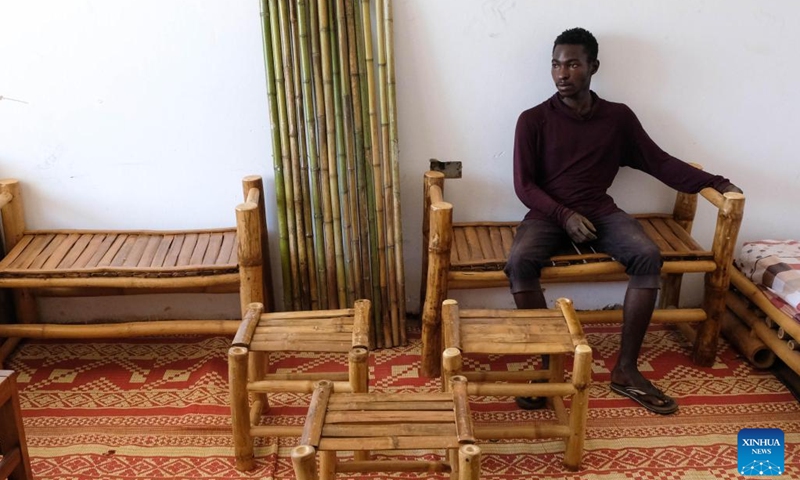 A staff member of the Uganda Bamboo Association sits on a bamboo bench in Kampala, Uganda, Oct. 26, 2022. The Uganda Bamboo Association brings related organizations and community members together to share information, resources and technology in growing and adding value to bamboo. The association organizes demonstrations for members on how to plant bamboo and also sensitizes them about the economic benefits of the plant.(Photo: Xinhua)