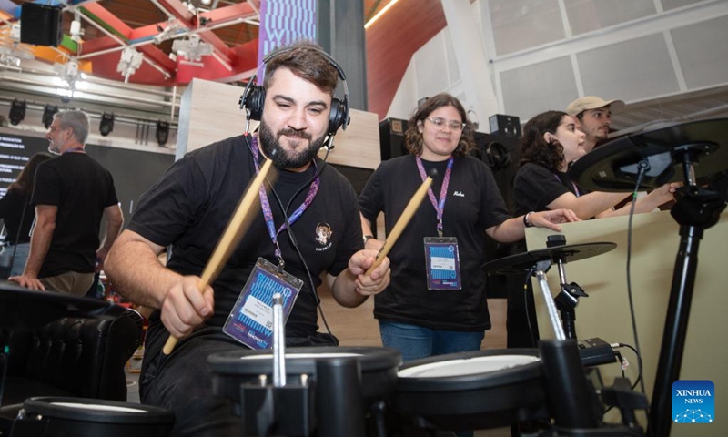 A staff member (C) demonstrates an electronic drum at Rio Innovation Week in Rio de Janeiro, Brazil, on Nov. 8, 2022. The four-day Rio Innovation Week opened in Rio de Janeiro on Tuesday. (Xinhua/Wang Tiancong)