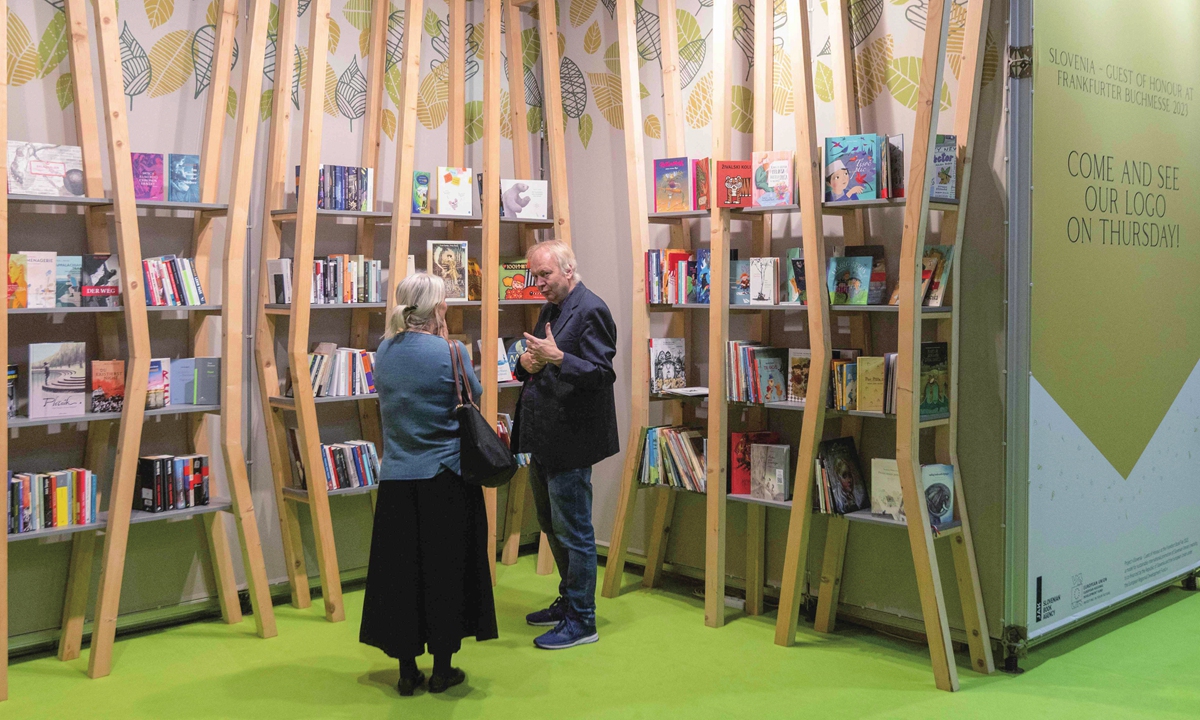 Visitors talk in front of a wall of books at the Frankfurt Book Fair in Germany on October 22, 2022. Photo: VCG