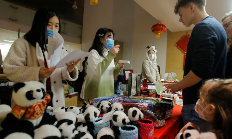 People visit the Chinese stand during a Christmas bazaar organized by the International Women's Association (IWA) at National Library of Romania in Bucharest, Romania, Dec. 11, 2022. (Photo by Cristian Cristel/Xinhua)