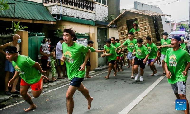 Residents run while carrying a hut made out of nipa palm during the Buhat Kubo (nipa hut carrying) race in Pasig City, the Philippines, Nov. 12, 2022. (Xinhua/Rouelle Umali)